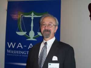 A Man in a Black Suit Beside a Poster