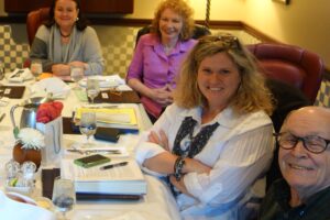 A Group of People Sitting by a Table With Books