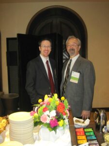 Two Men in Suits Standing by a Table