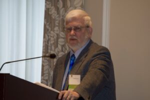 A Man in a Brown Color Jacket by a Podium