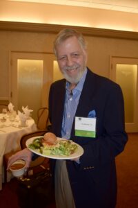 A Man in a Black Color Jacket With a Plate of Food