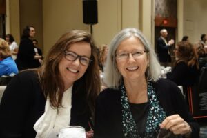 Two Women in Glasses Smiling at Each Other