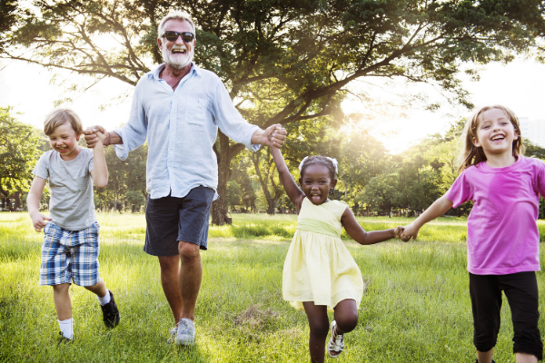 A Man Dancing With Children on a Green Field